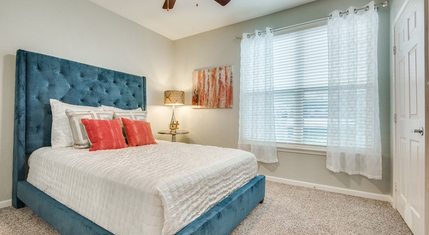 a bedroom with a blue headboard and a ceiling fan at The  Sophia